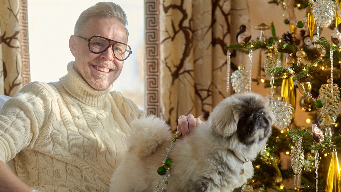 Person holding a dog in a decorated room with Christmas decorations