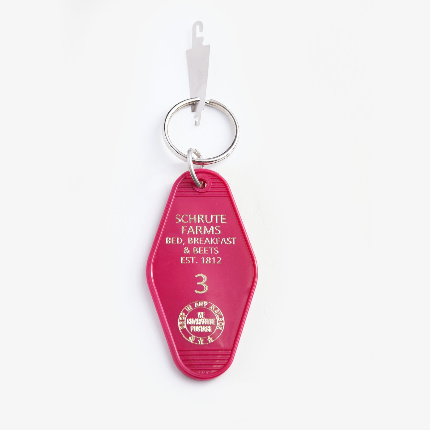 Pink keychain with 'Schrute Farms' text on a white background