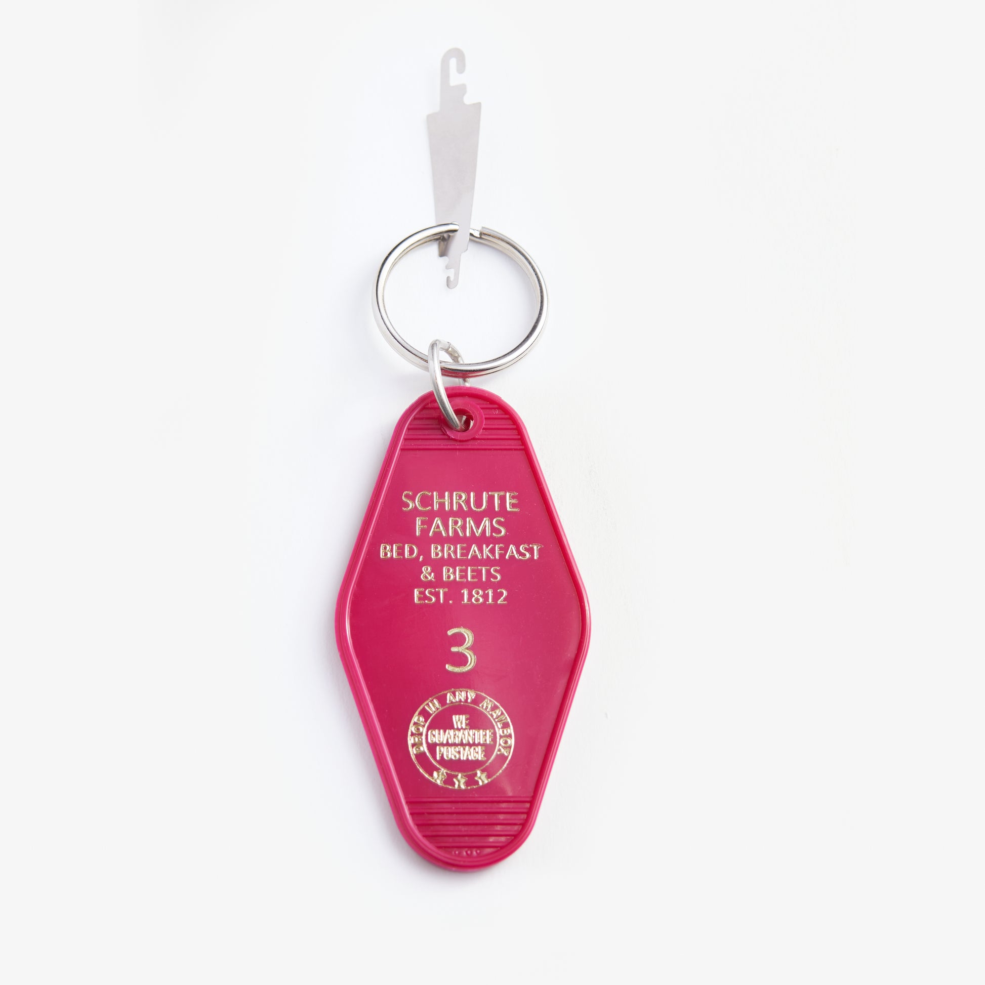 Pink keychain with 'Schrute Farms' text on a white background