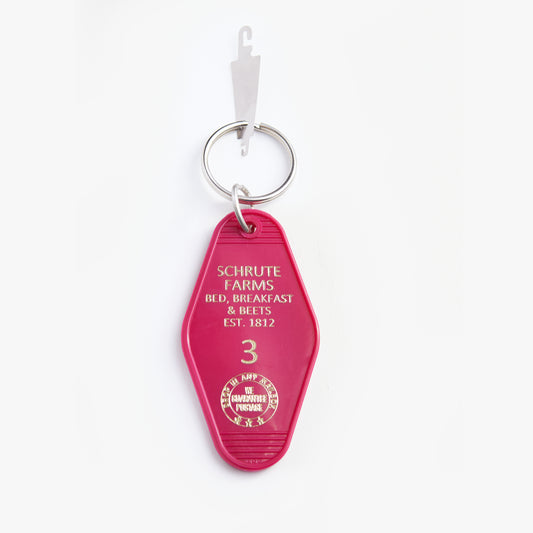 Pink keychain with 'Schrute Farms' text on a white background