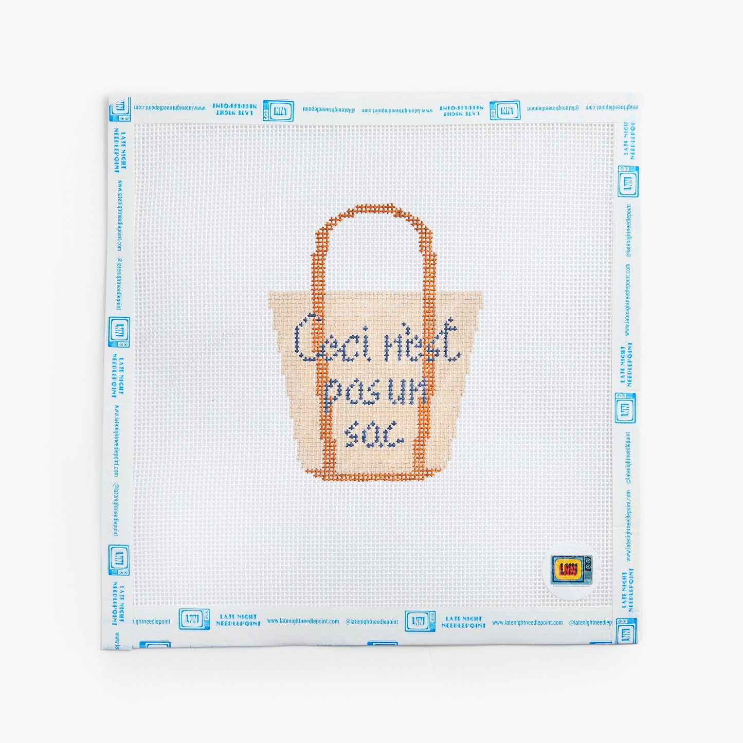 Cross-stitched tote bag design on a white fabric with blue grid lines