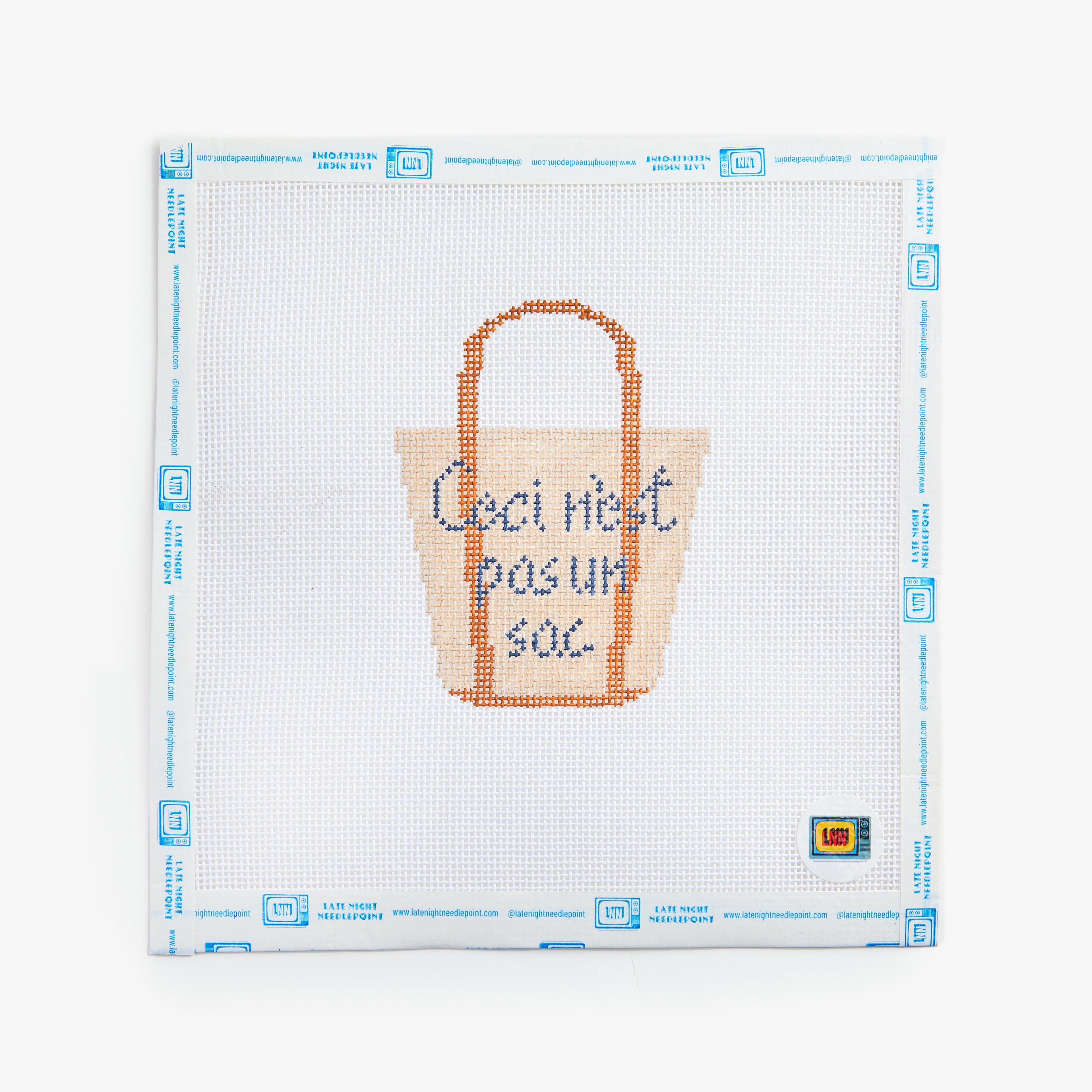 Cross-stitched tote bag design on a white fabric with blue grid lines