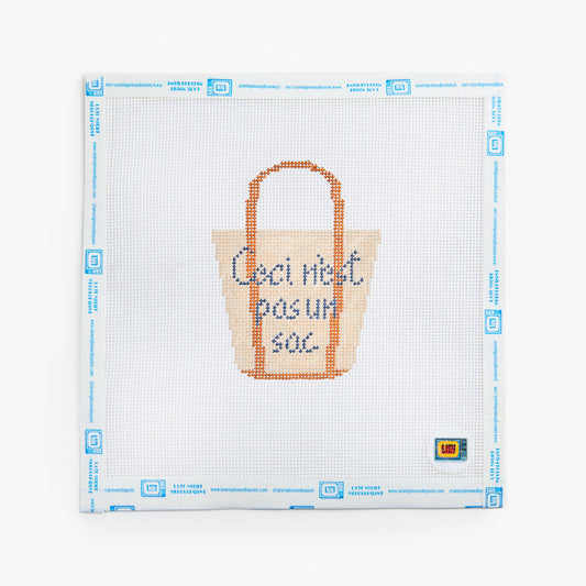 Cross-stitched tote bag design on a white fabric with blue grid lines
